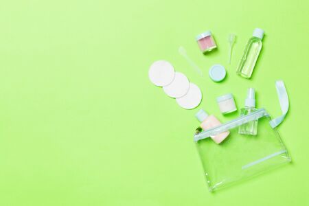 Set of travel size cosmetic bottles on green background. Flat lay of cream jars. Top view of bodycare style concept.の写真素材