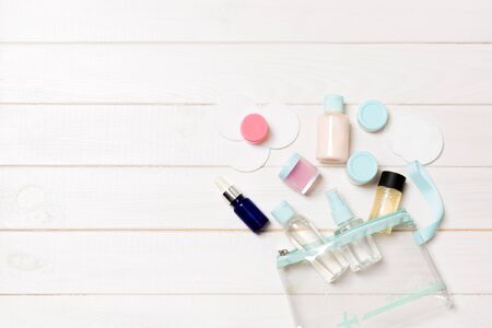 Set of travel size cosmetic bottles on white wooden table background. Flat lay of cream jars. Top view of bodycare style concept.の写真素材