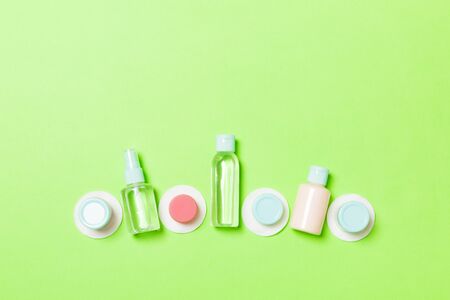Top view composition of small travelling bottles and jars for cosmetic products on green background. Facial skin care concept with copy space for your design.の写真素材