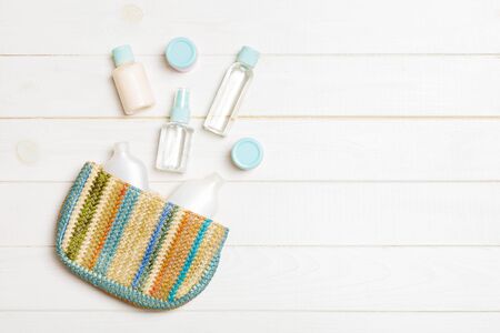 Woman cosmetic bag with set of beauty product and bodycare cream on white wooden background with copy space for you design.の写真素材