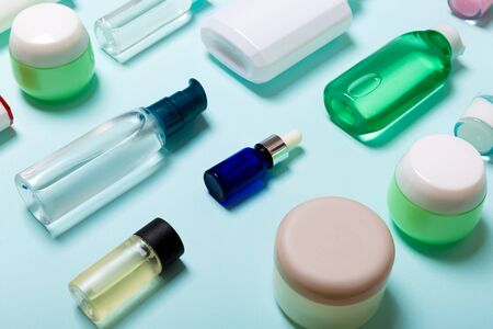 Top view of cosmetic products in different jars and bottles on blue background. Close-up of containers with copy space.の写真素材