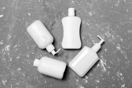 Set of White Cosmetic containers isolated on yellow background, top view with copy space. Group of plastic bodycare bottle containers with empty space for you design.の写真素材