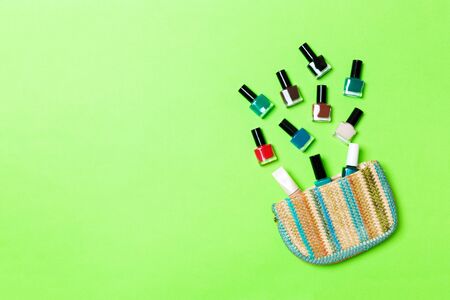 Woman cosmetic bag with manicure and pedicure, bright gel varnishes on green background with copy space for your design and text. Nail work flat lay concept.の写真素材