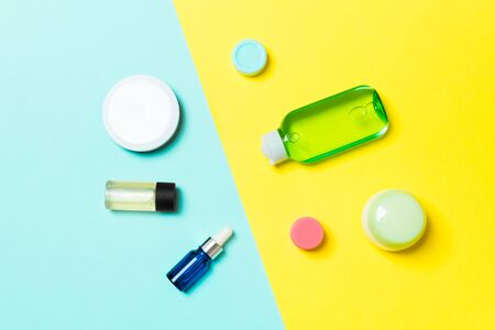 Top view of cosmetic containers, sprays, jars and bottles on yellow and blue background. Close-up view with empty space for your design.の写真素材