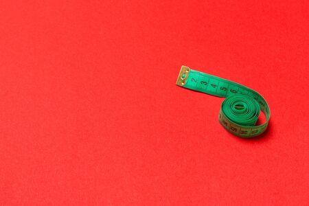 Top view of curled measuring tape as a sewing accessory on red background. Tailor concept with copy space.の写真素材