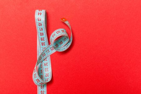 Top view of measuring tape on red background. Tailor and slim waist concept with emty space for your idea.の写真素材