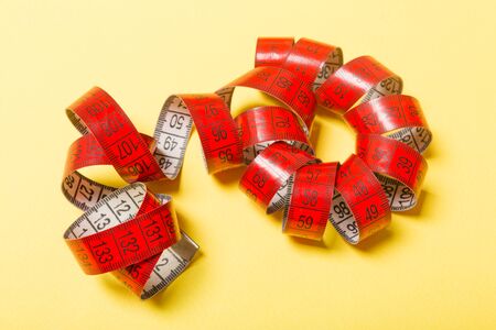 Perspective view of curled measure tape on yellow background. Keeping fit concept.の写真素材