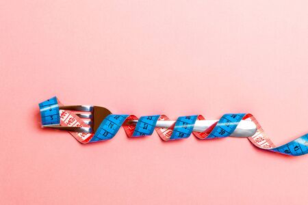 Top view of obesity concept with fork wrapped in measuring tape on blue background.