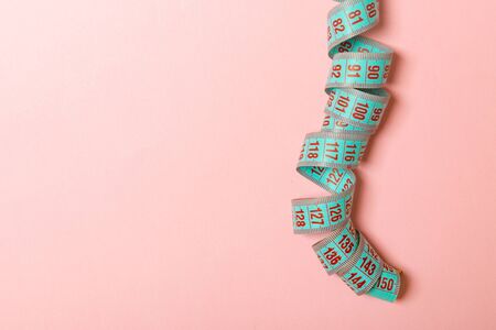 Rolled tape measure with space for your design. Top view of slim waist concept on pink background.の写真素材