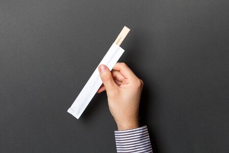 Crop image of male hand holding chopsticks on black background. Japanese food concept with copy space.の写真素材