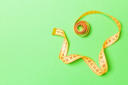 Rolled tape measure with space for your design. Top view of slim waist concept on green background.