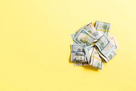 Stacks of one hundred dollars banknotes close-up on colored background business concept top view...