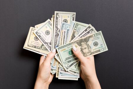 Top view of different dollar banknotes in female hands on colorful background. Business and financial concept.の写真素材