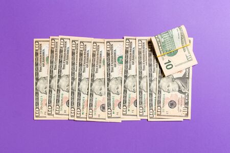 Top view of lying 10 dollar banknotes in one line on colorful background. Close up of money saving concept.の写真素材