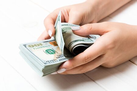 Perspective view of female hands counting money. One hundred dollar banknotes on wooden background. Salary concept. Bribe concept.の写真素材