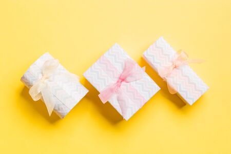 wrapped present in paper with Colored ribbon on yellow background. Present box, decoration of gift...