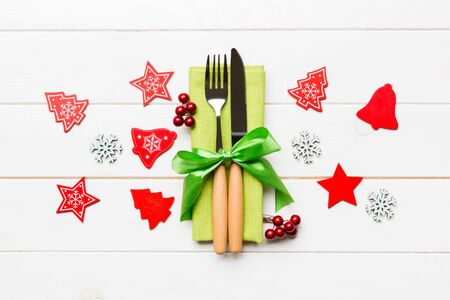 Top view of New Year dinner on wooden background. Festive cutlery on napkin with christmas decorations and toys. Close up of family holiday concept.の写真素材
