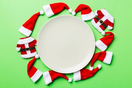 Festive set of plate decorated with Santa Claus hat on colorful background. Top view christmas dinner concept.の写真素材