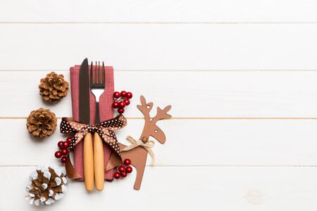 New year set of fork and knife on napkin. Top view of christmas decorations and reindeer on wooden background. Holiday family dinner concept with empty space for your design.の写真素材