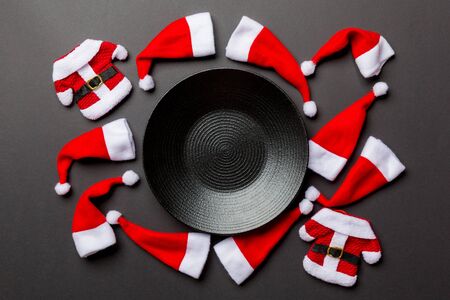 Festive set of plate decorated with Santa Claus hat on colorful background. Top view christmas dinner concept.の写真素材