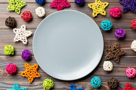 Top view of holiday plate decorated with knitted baubles and stars on wooden background.の写真素材