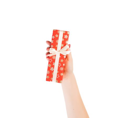 Woman hands give wrapped Christmas or other holiday handmade present in red paper with Gold ribbon. Isolated on white background, top view. thanksgiving Gift box concept.の写真素材