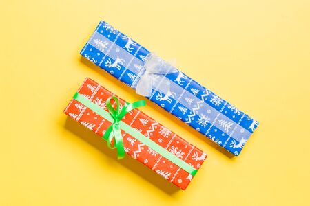 Gift box with white and green bow for Christmas or New Year day on yellow background, top view.の写真素材