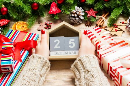 Top view of female hands holding a calendar on wooden background. The twenty fifth of December....
