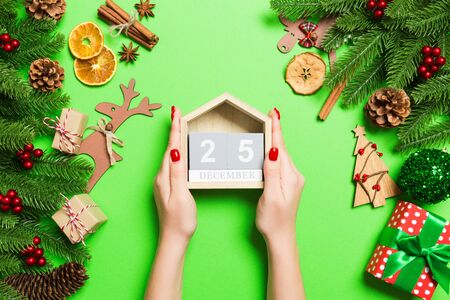 Top view of female hands holding calendar on green background. The twenty fifth of December. Holiday decorations. Christmas time concept.の写真素材