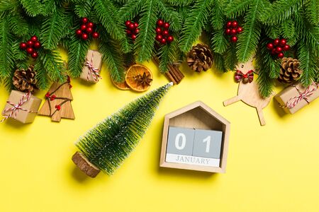Top view of female hands holding calendar on yellow background. The first of January. Holiday decorations. New Year concept.の写真素材