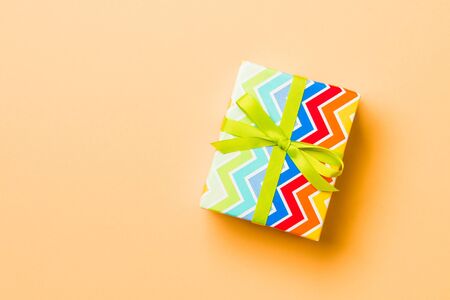Top view Christmas present box with green bow on orange background with copy space.