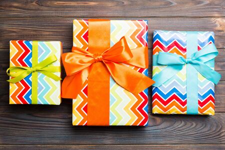 paper gift box with colored ribbon on dark wood background. top view with copy space Christmas holiday concept .の写真素材