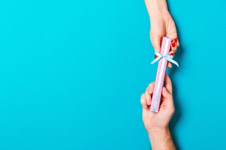 Top view of a man and a woman congratulating each other with a gift on colorful background. Surprise...