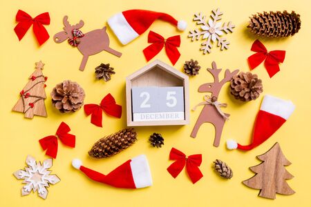 Christmas yellow background with holiday toys and decorations. Top view of wooden calendar. The twenty fifth of December. Merry Christmas concept.の写真素材