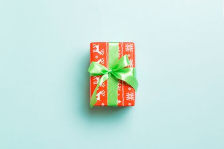 Gift box with green bow for Christmas or New Year day on blue background, top view with copy space.の写真素材