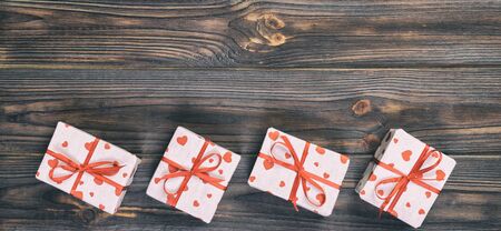 Valentine or other holiday handmade present in paper with red hearts and gifts box in holiday wrapper. Present box of gift on dark wooden table top view with copy space, empty space for design.の写真素材