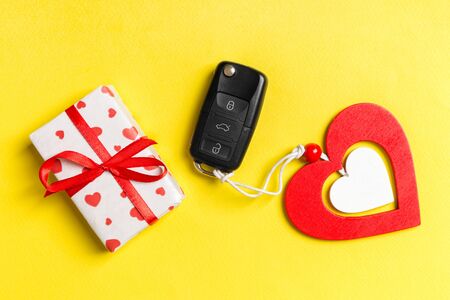Top view of gift box, car key and wooden heart on colorful background. Luxury present for Valentine's day.の写真素材