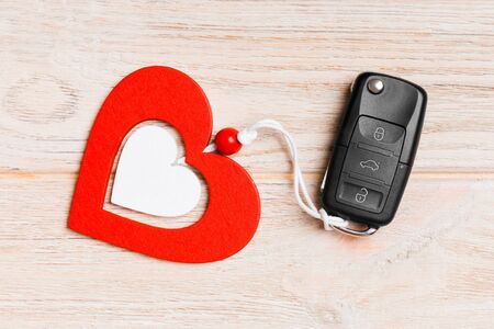 Top view of a present for Valentine's Day on wooden background. Close up of car key and heart. Surprise concept for a holiday.の写真素材