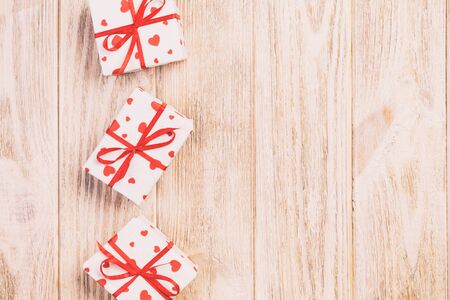 Valentine or other holiday handmade present in paper with red hearts and gifts box in holiday wrapper. Present box of gift on orange wooden table top view with copy space, empty space for design.の写真素材