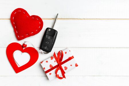 Top view of a present for Valentine's Day on wooden background. Car key, gift box and heart with copy space. Surprise concept for a holiday.の写真素材