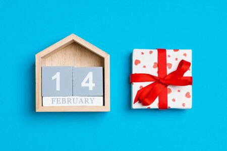 Top view of white gift boxes with hearts and wooden calendar on colorful background. The fourteenth of February. Valentine's Day concept.の写真素材