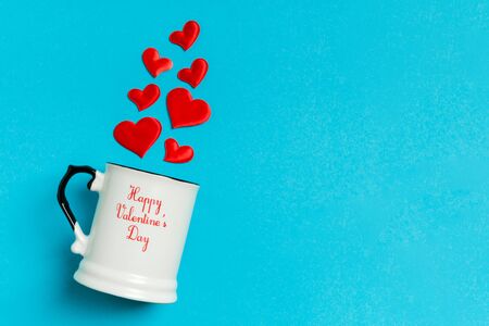 Top view composition of red hearts falling out from a cup on colorful background with copy space. Romantic relationship concept. St Valentaine's Day.の写真素材