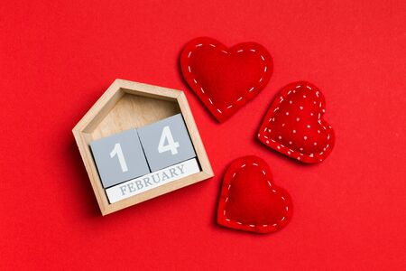 Top view of wooden calendar and textile hearts on colorful background. The fourteenth of February....