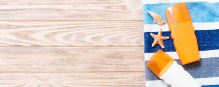 Top view of Beach flat lay banner accessories. sunscreen bottle with seashells, starfish, towel and...