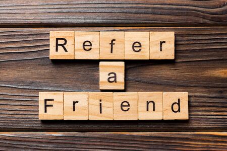 refer a friend word written on wood block. refer a friend text on table, concept.の写真素材