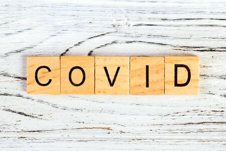 Inscription COVID on wooden background. Covid word written on wood block. text on wooden tableの写真素材