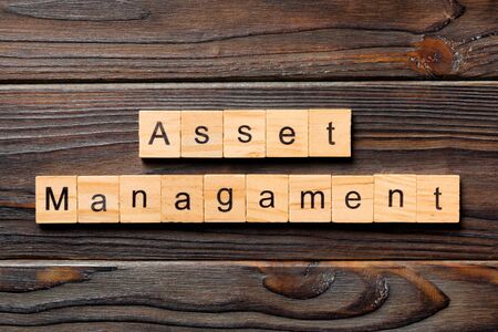Asset management word written on wood block. Asset management text on wooden table for your desing, Top view concept.の写真素材