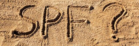 Sun protect factor concept. SPF word written on the beach with question mark.の写真素材