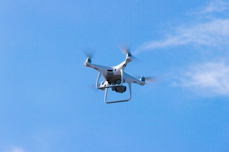 Quadcopter drone is flying in the blue sky. Unmanned aerial vehicle. Remote video shooting from a height. Modern digital camera.の写真素材