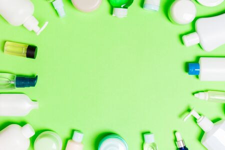 Frame of plastic bodycare bottle Flat lay composition with cosmetic products on green background empty space for you design. Set of White Cosmetic containers, top view with copy space.の写真素材